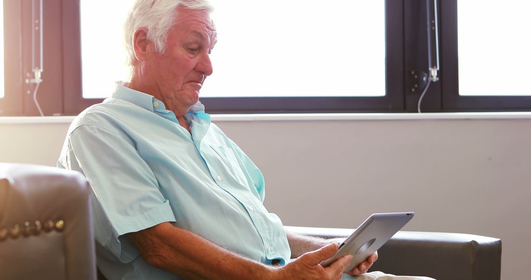 Senior man using digital tablet while sitting by window - Free Images, Stock Photos and Pictures on Pikwizard.com