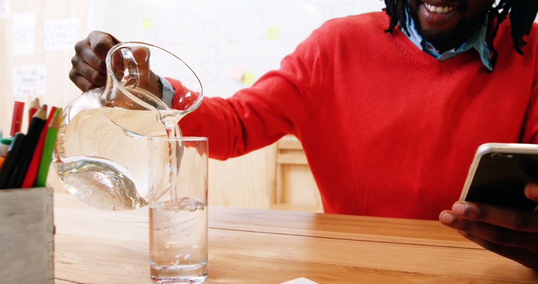 Man Hydrating with Water While Using Phone at Work