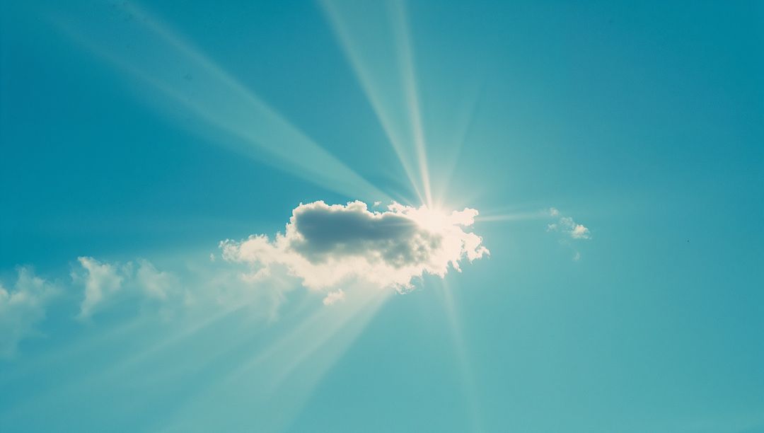 Sun Rays Illuminating Cloud in Clear Blue Sky