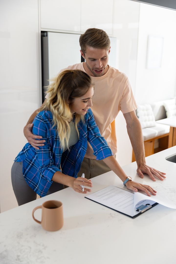 Happy Couple Reviewing Documents in Modern Kitchen at Home