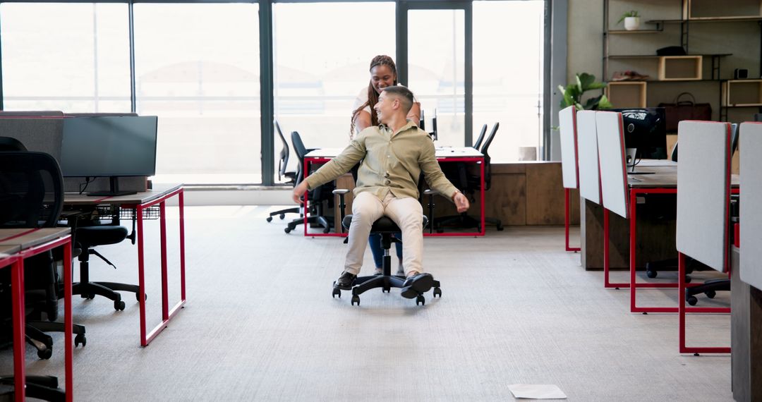 Colleagues Playfully Spin in Scenic Modern Workspace, Laughing and Bonding