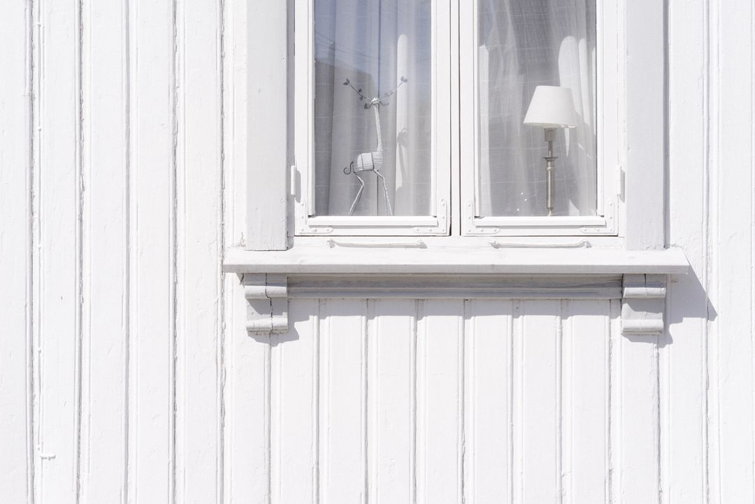 Minimalist white wooden facade featuring double window with sheer curtains floor lamp and decor