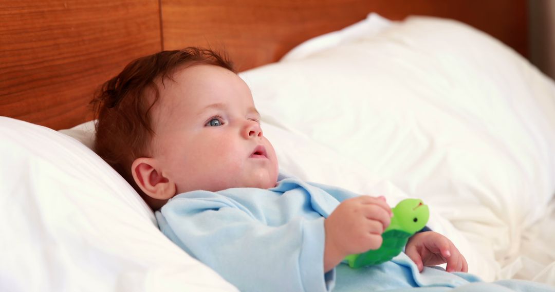 Adorable Baby Lying on Bed Holding Toy - Free Images, Stock Photos and Pictures on Pikwizard.com