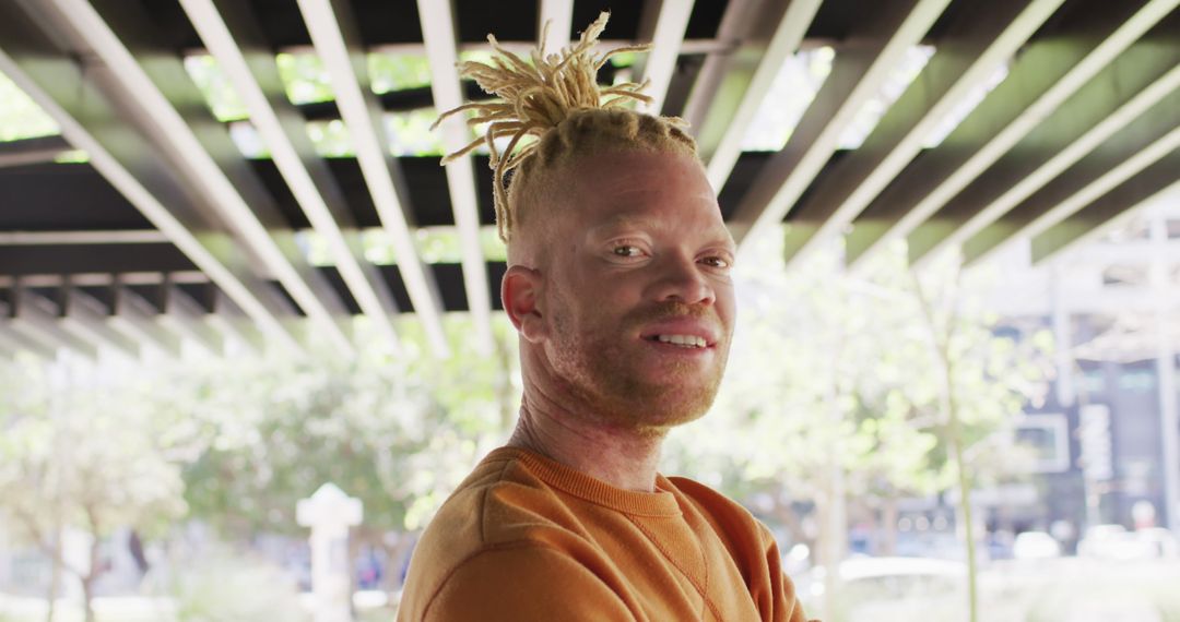 Confident Man with Albinism Smiling Under Urban Canopy - Free Images, Stock Photos and Pictures on Pikwizard.com