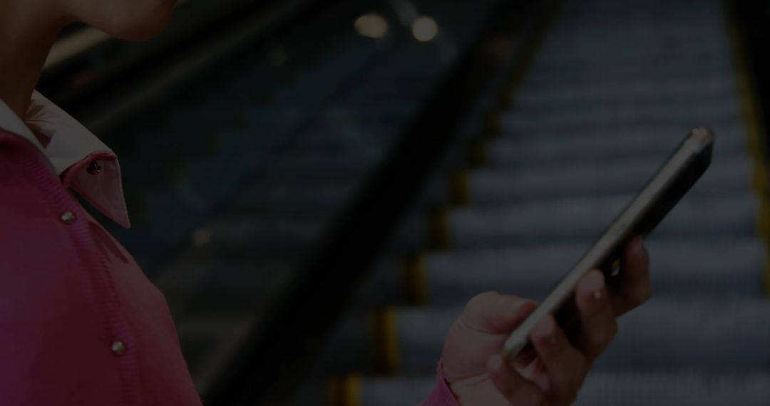 Commuter in Pink Coat Using Smartphone On Escalator