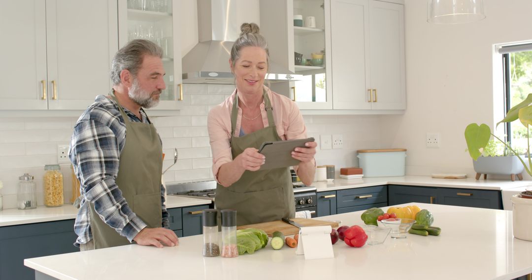 Senior Couple Cooking Meal Together in Modern Kitchen Using Tablet