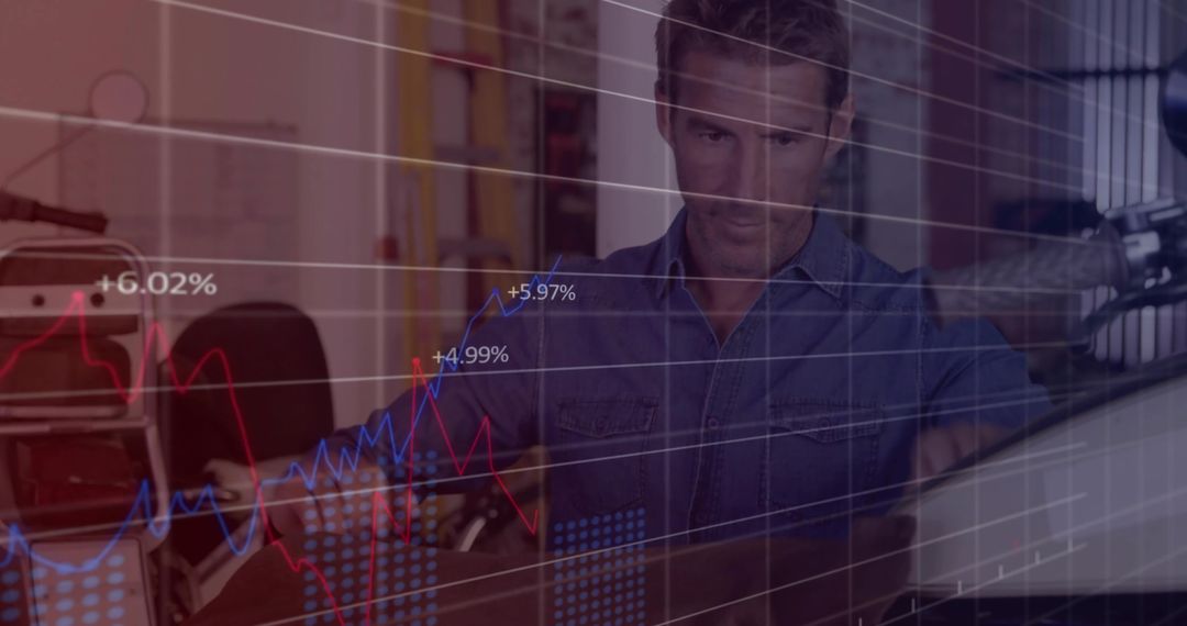 Man analyzing financial charts on desktop in home studio with microphone and suitcase