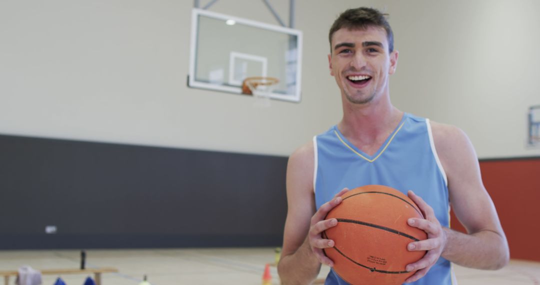 Smiling Young Man Holding Basketball on Indoor Court - Free Images, Stock Photos and Pictures on Pikwizard.com