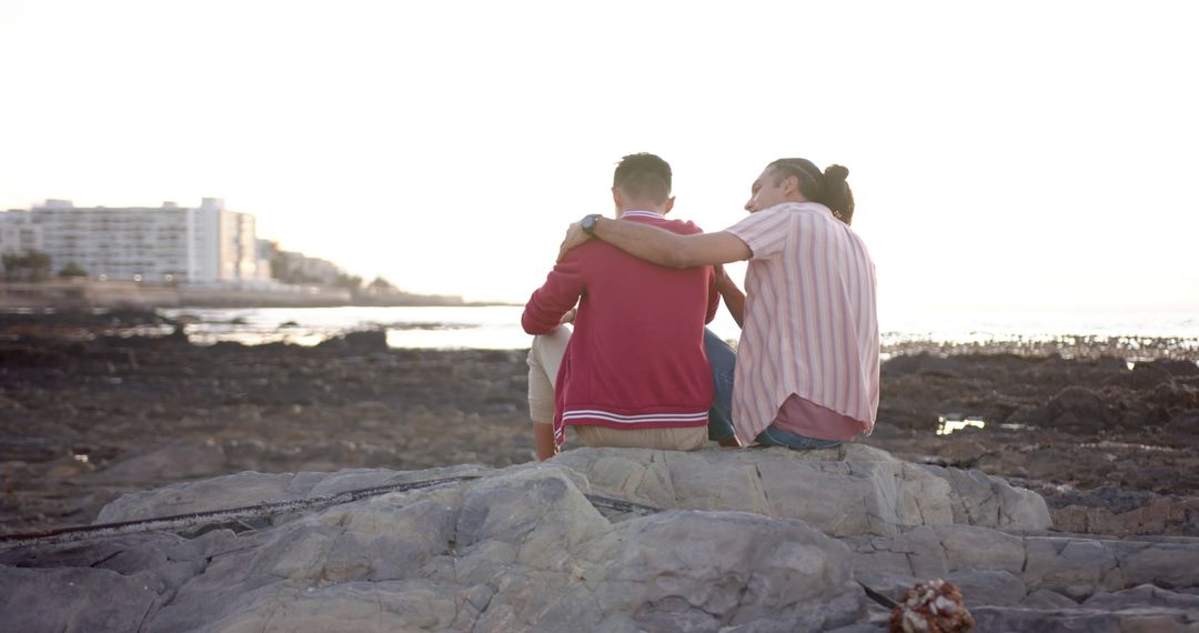 Couple Sitting on Rocks By The Sea Enjoying Sunset - Free Images, Stock Photos and Pictures on Pikwizard.com