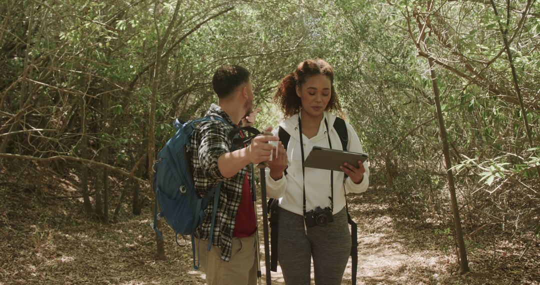 Happy Couple Hiking and Using Tablet in Sunny Forest
