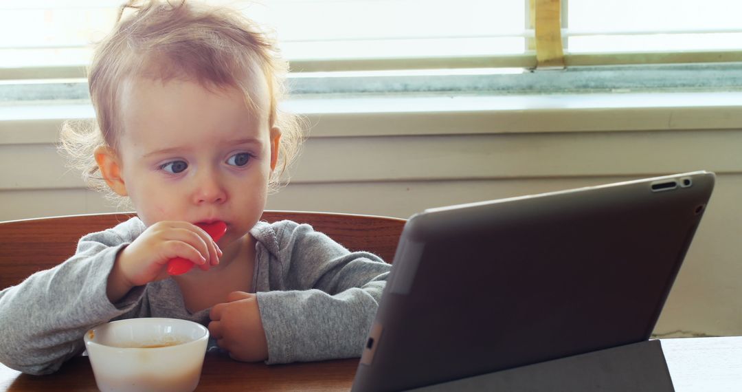 Toddler Engaged with Tablet During Breakfast Time - Free Images, Stock Photos and Pictures on Pikwizard.com