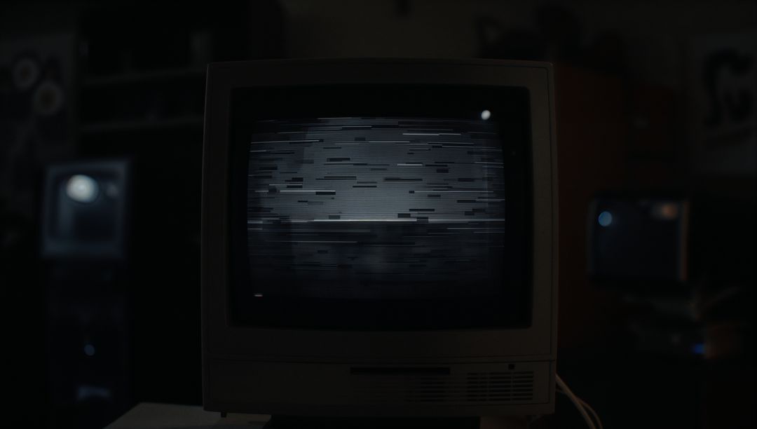 Vintage CRT Monitor Displaying Glitchy Screen in Dimly Lit Workshop