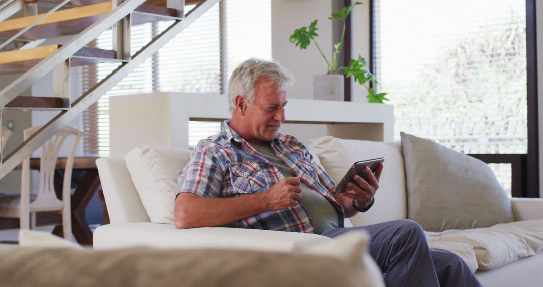 Smiling Senior Man Using Tablet in Modern Living Room - Free Images, Stock Photos and Pictures on Pikwizard.com