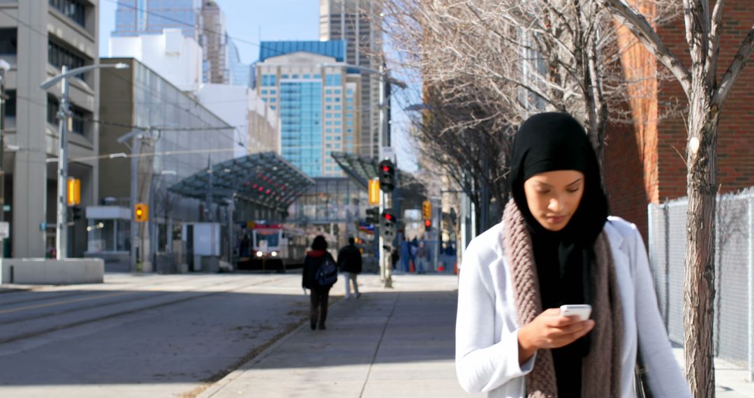 Young Woman in Hijab Using Smartphone in Urban Setting - Free Images, Stock Photos and Pictures on Pikwizard.com