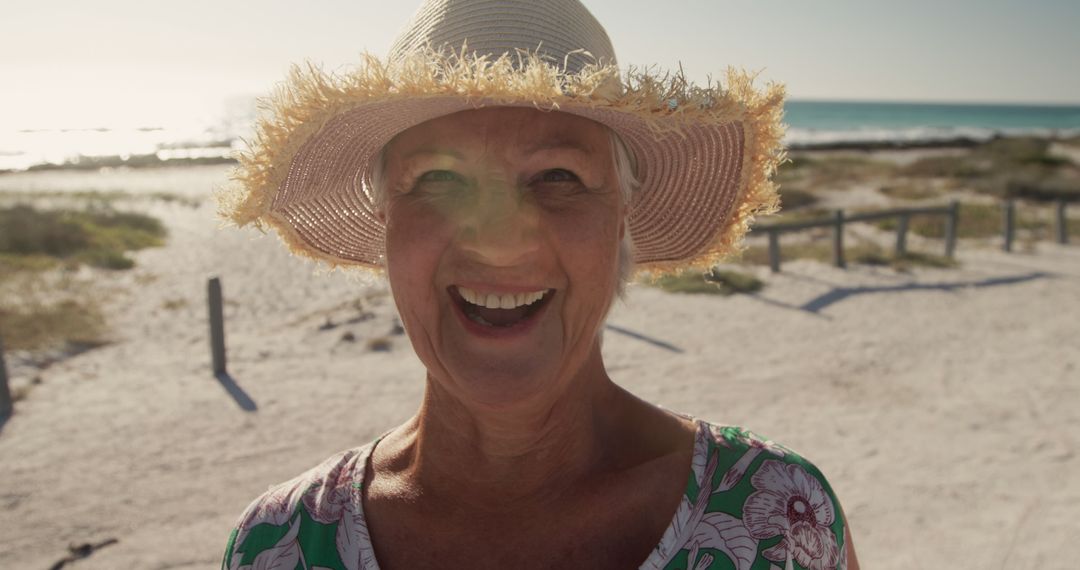 Happy Elderly Woman Enjoying a Sunny Day at the Beach - Free Images, Stock Photos and Pictures on Pikwizard.com