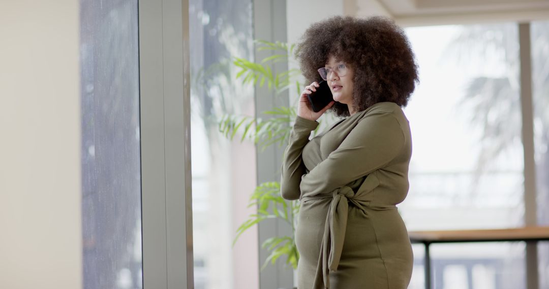 African American businesswoman talking on phone standing at window - Free Images, Stock Photos and Pictures on Pikwizard.com