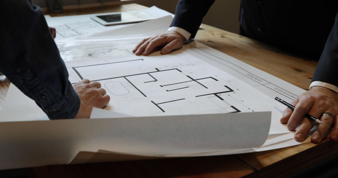 Architects Collaborating on Building Blueprints During Office Meeting