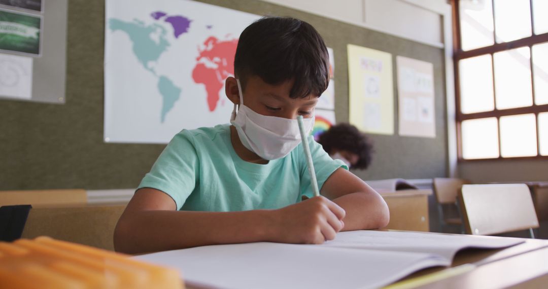 Young Boy Wearing Face Mask Writing in Classroom - Free Images, Stock Photos and Pictures on Pikwizard.com