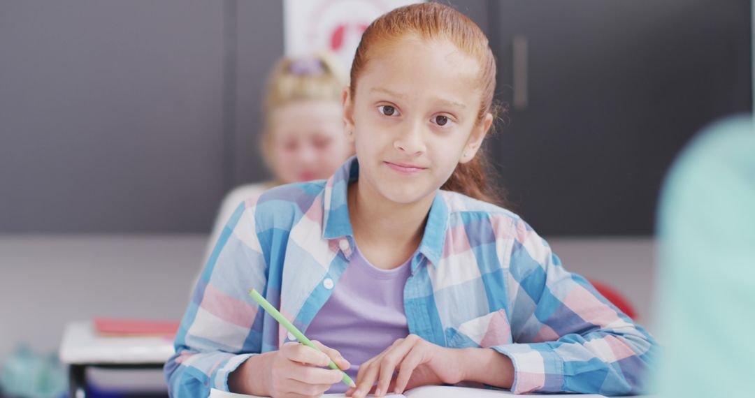 Smiling Schoolgirl Writing in Classroom Engaged in Learning Activity