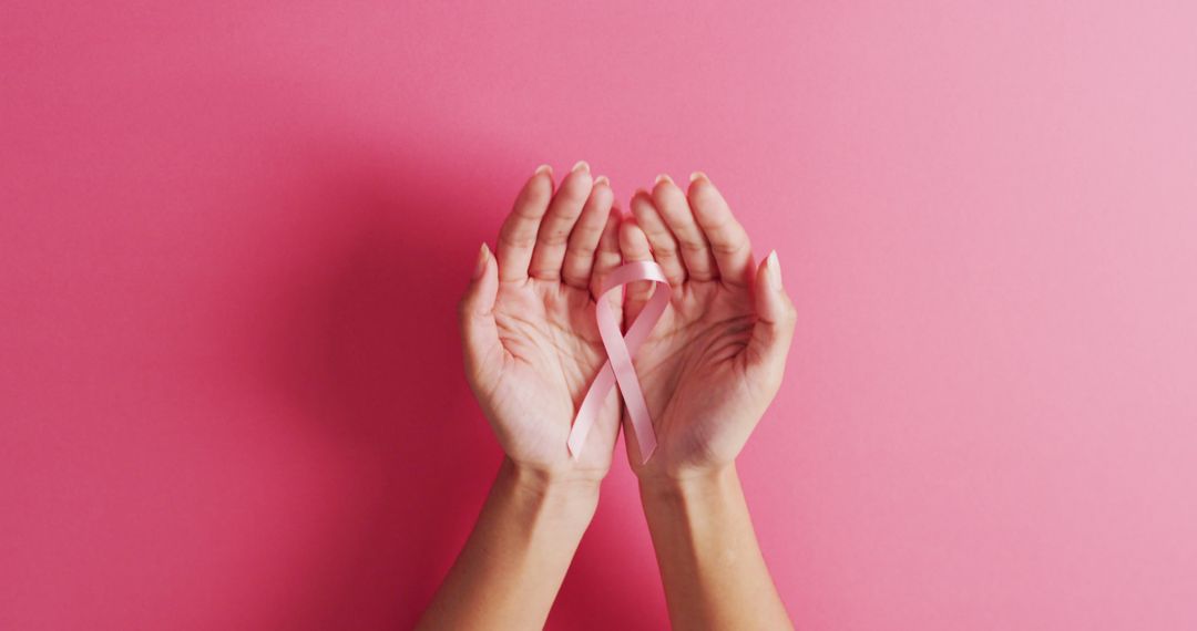 Image of hands of caucasian woman holding pink ribbon on pink background - Free Images, Stock Photos and Pictures on Pikwizard.com