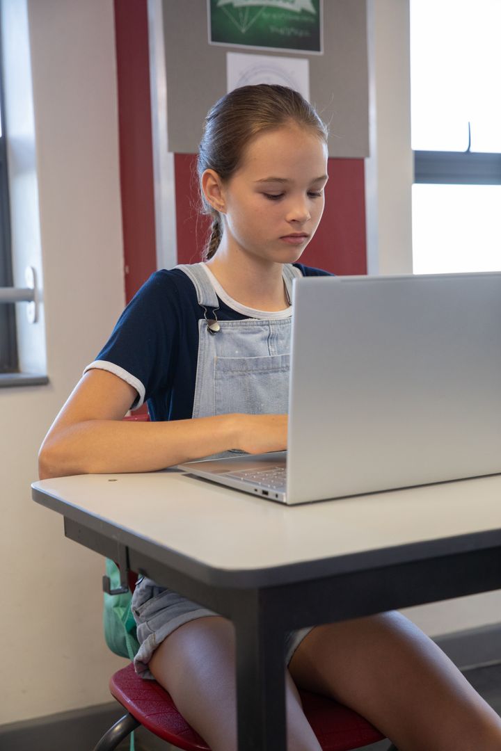 Focused Young Student Typing on Laptop in Classroom
