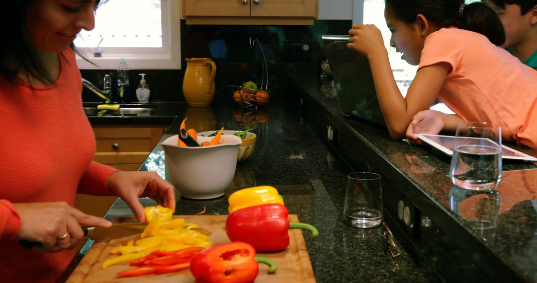 Mother Preparing Vegetables in Kitchen While Children Watch Tablet - Free Images, Stock Photos and Pictures on Pikwizard.com