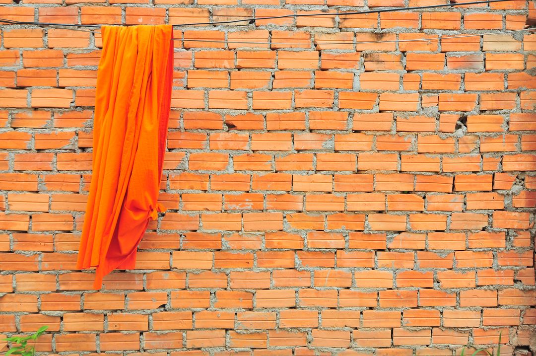 Vibrant Orange Fabric Draped Over Brick Wall - Free Images, Stock Photos and Pictures on Pikwizard.com