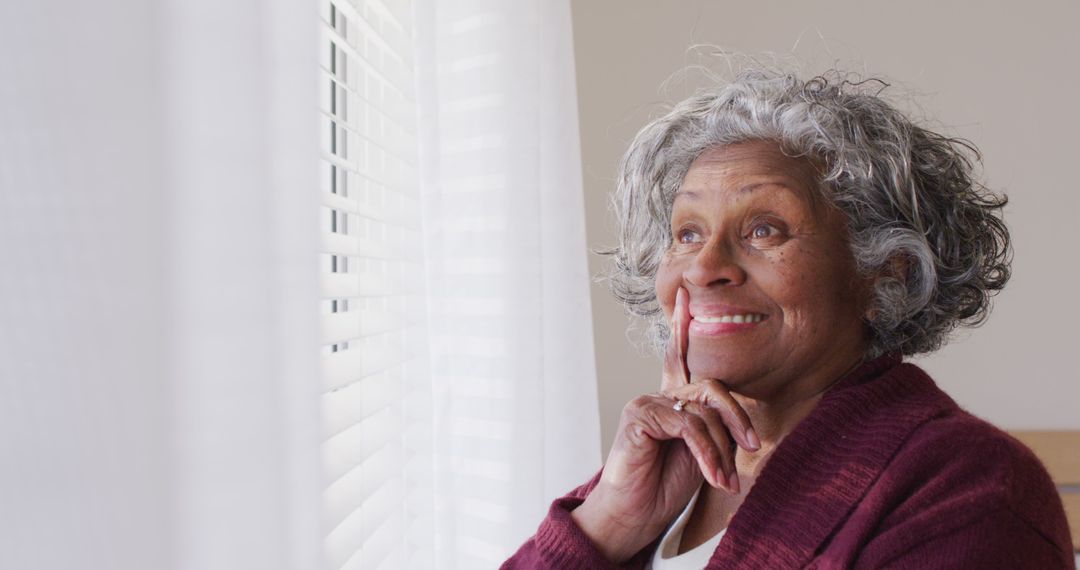 Happy senior african american woman looking through window - Free Images, Stock Photos and Pictures on Pikwizard.com