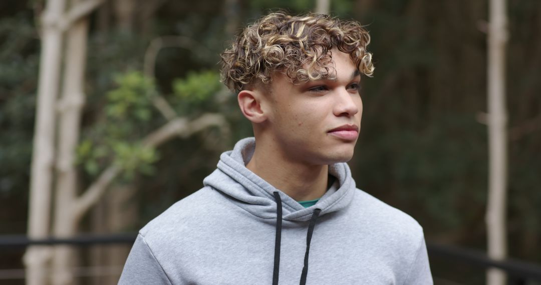 Young Man in Gray Hoodie Exploring Forest Environment