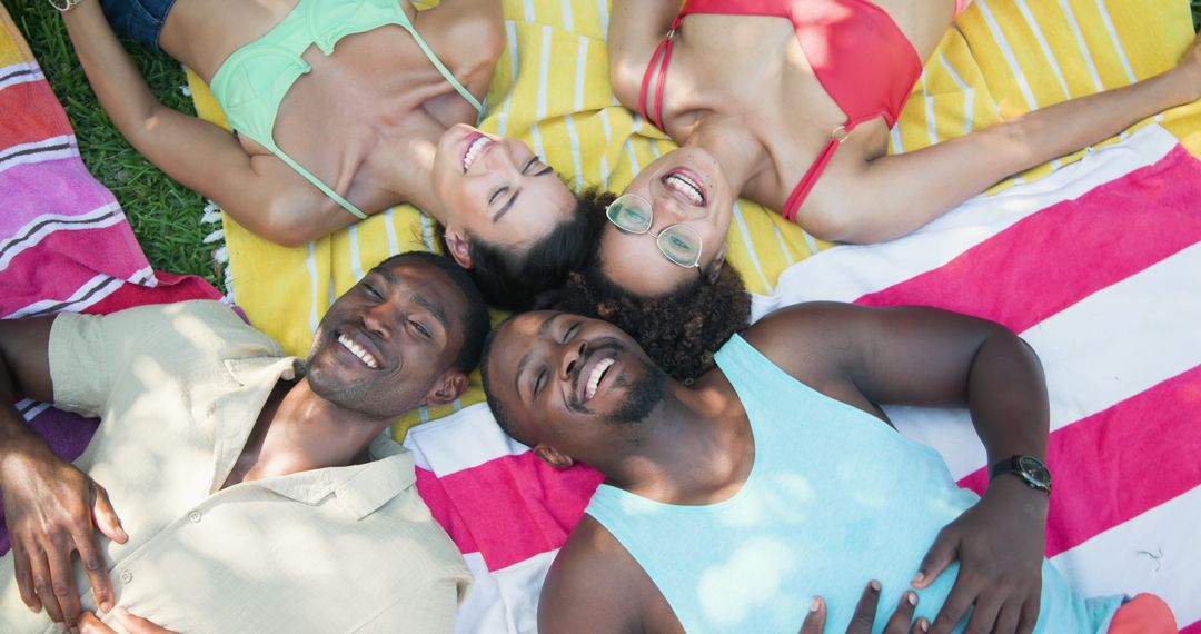 Smiling Friends Relaxing on Picnic Blankets in Summer Sunlight