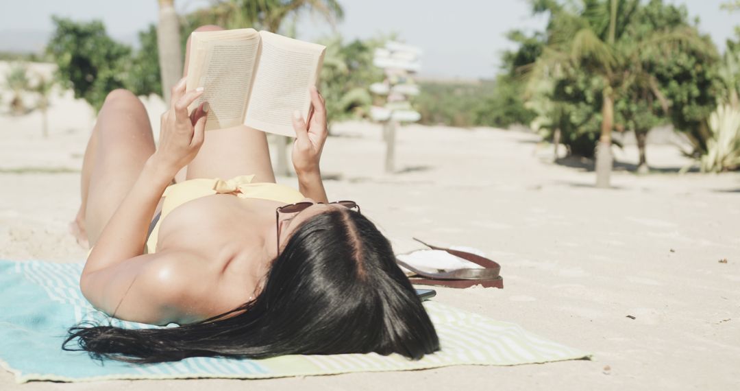 Woman Reading a Book while Sunbathing on Sunny Beach - Free Images, Stock Photos and Pictures on Pikwizard.com