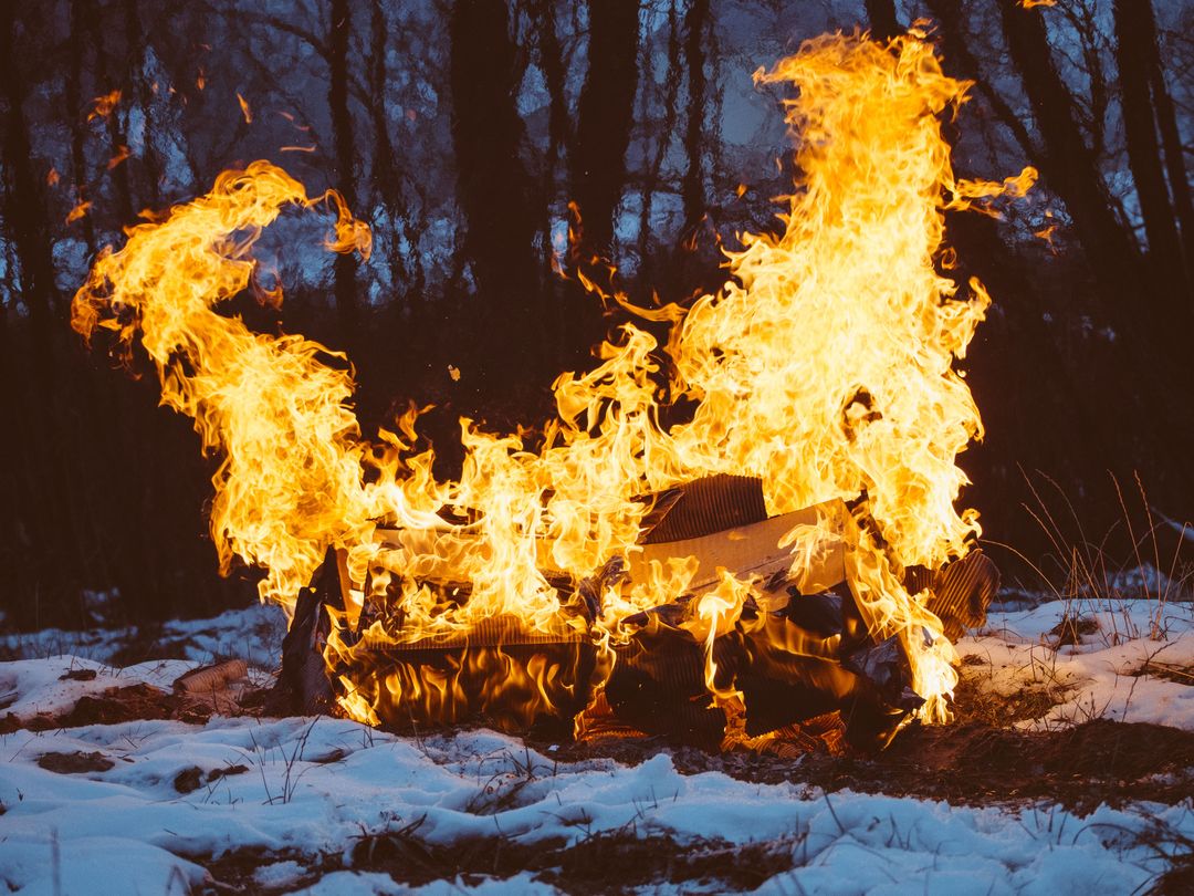 Burning Couch in Snowy Forest at Dusk with Intense Flames and Dramatic Smoke