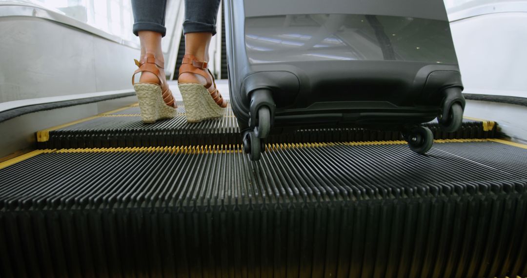 Low Angle View of Traveler in Heeled Sandals on Escalator with Suitcase - Free Images, Stock Photos and Pictures on Pikwizard.com