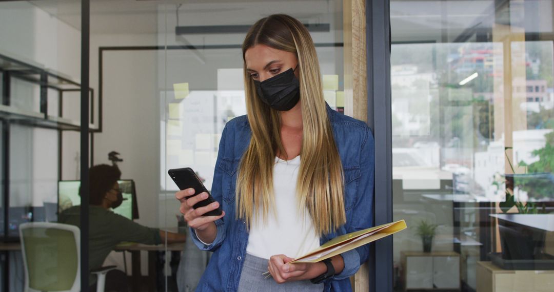 Businesswoman in Office Wearing Protective Mask Using Smartphone - Free Images, Stock Photos and Pictures on Pikwizard.com