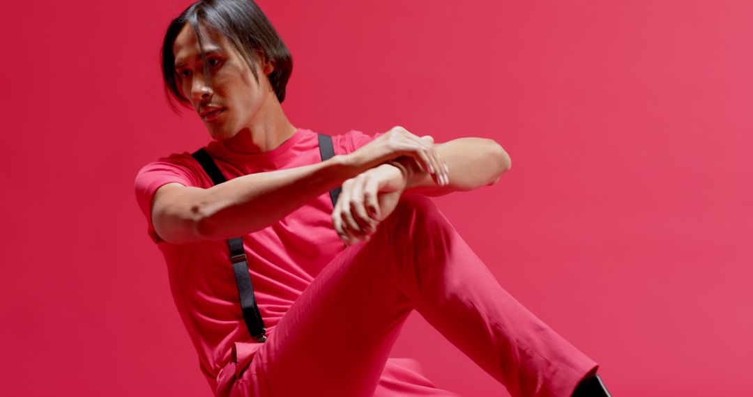 Stylish Asian Man in Monochrome Outfit on Red Studio Backdrop