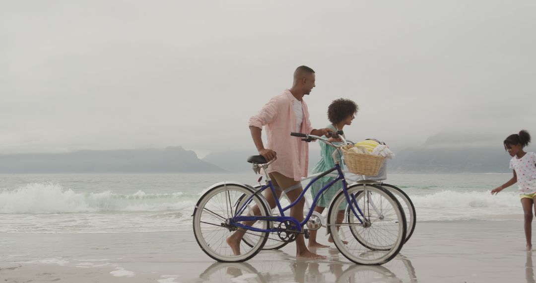 Young Family Enjoying Beach Day with Bicycles and Smiling Daughter - Free Images, Stock Photos and Pictures on Pikwizard.com