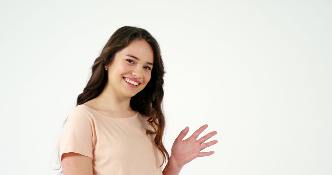 Cheerful Young Woman Waving Hand on Light Background - Free Images, Stock Photos and Pictures on Pikwizard.com