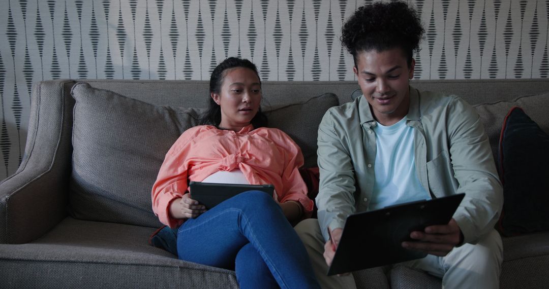 Couple Relaxing on Couch with Tablets and Documents