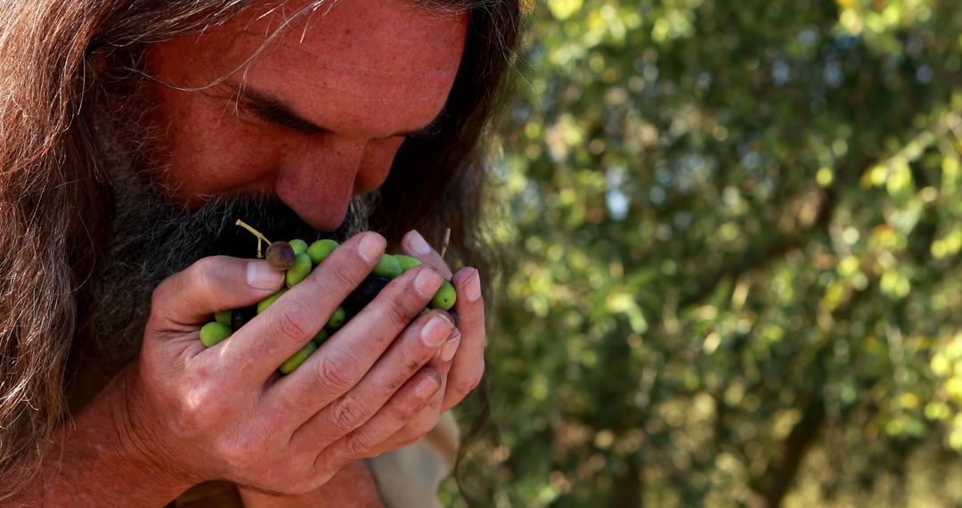 Man Smelling Freshly Picked Green Grapes Outdoors in Vineyard - Free Images, Stock Photos and Pictures on Pikwizard.com