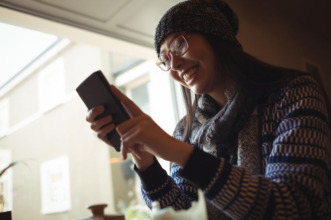 Image of a woman using her smartphone and laughing near a window - The importance of positive customer reviews - Image