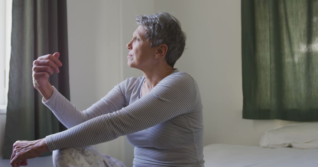 Contemplative Older Woman Sitting on Bed in Daylight - Free Images, Stock Photos and Pictures on Pikwizard.com