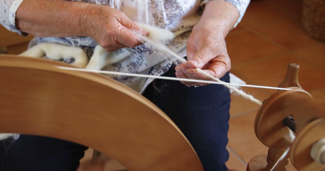 Elderly Woman Using Spinning Wheel to Spin Yarn - Free Images, Stock Photos and Pictures on Pikwizard.com