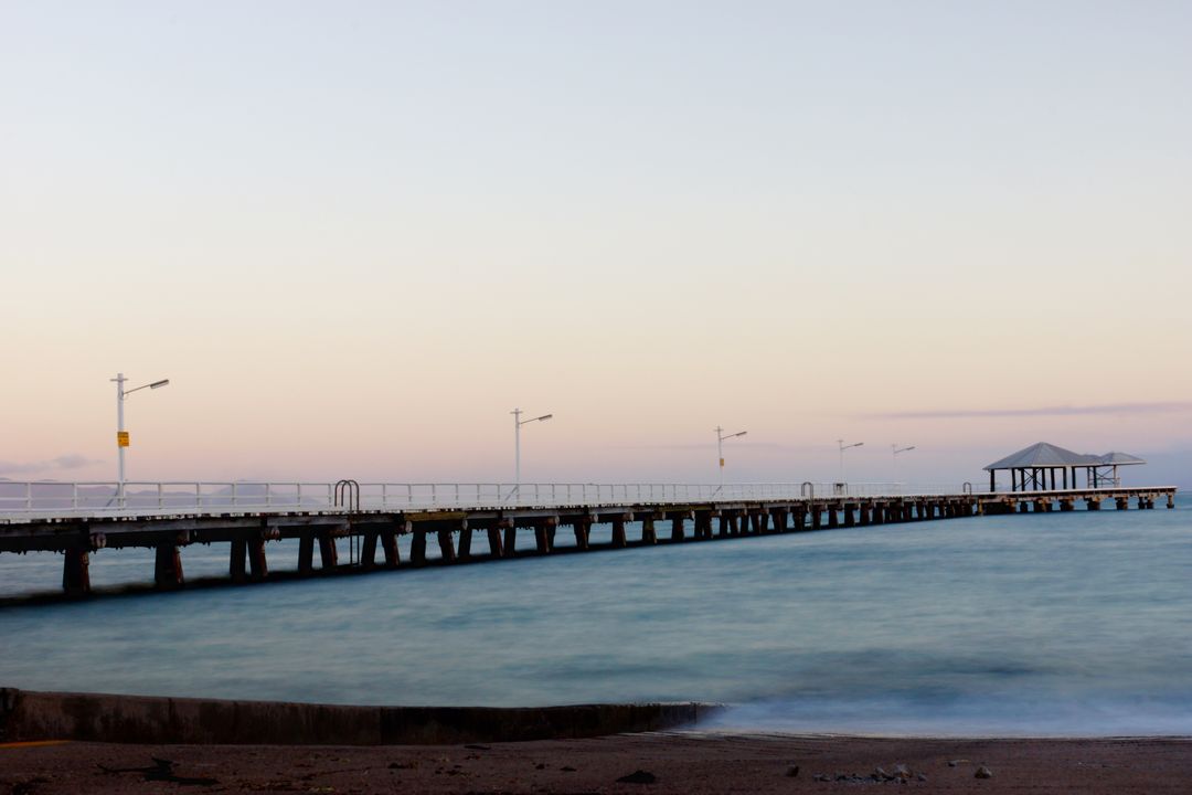 Long Wooden Pier Extending into Calm Ocean During Sunset - Free Images, Stock Photos and Pictures on Pikwizard.com