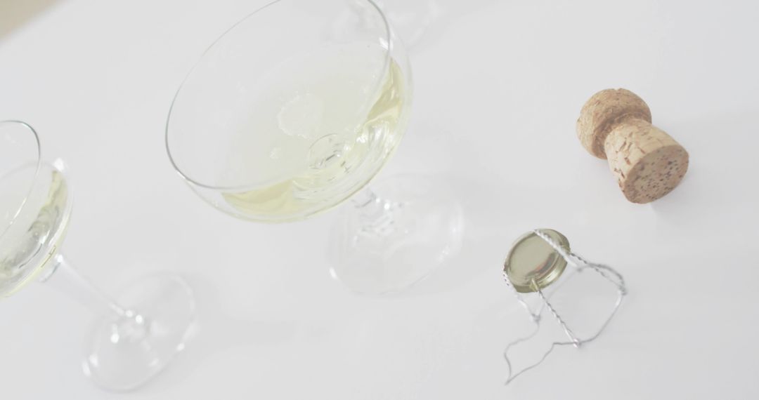 Minimal Champagne Coupe with Sparkling Bubbles, Cork and Wire Muselet on White High-Key Backdrop