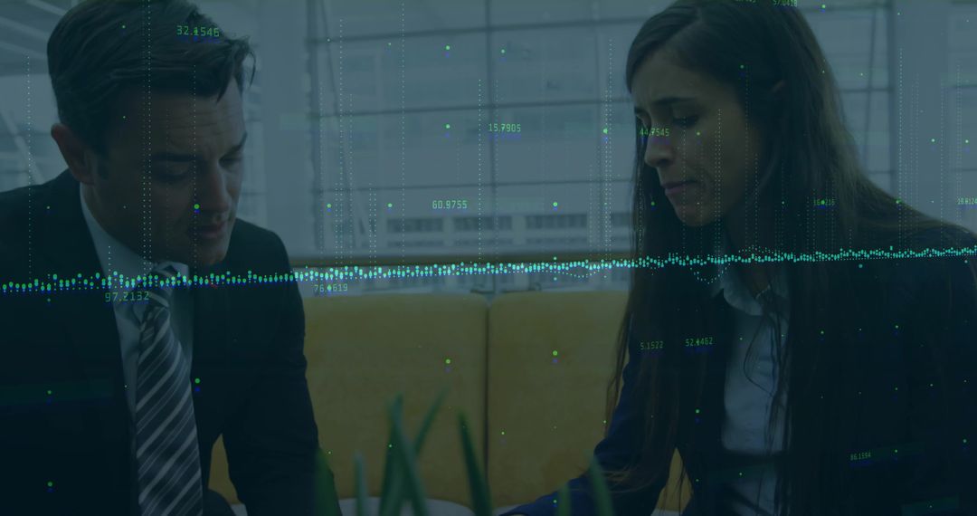 Colleagues Collaborating Over Digital Data in Modern Office Lounge