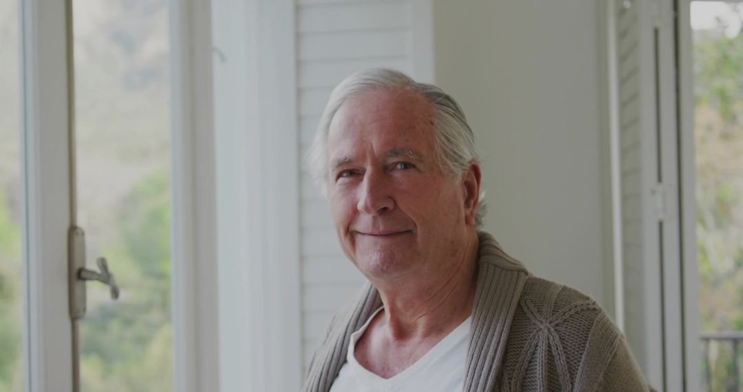 Smiling Senior Man By Window Reflecting Tranquil Lifestyle