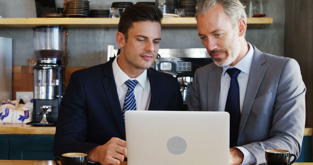 Businessmen Collaborating on Laptop Over Coffee at Cafe - Free Images, Stock Photos and Pictures on Pikwizard.com