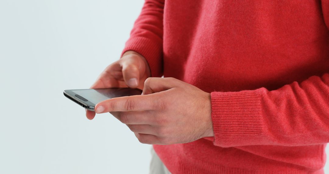 A person in a red sweater is using a smartphone, with copy space - Free Images, Stock Photos and Pictures on Pikwizard.com