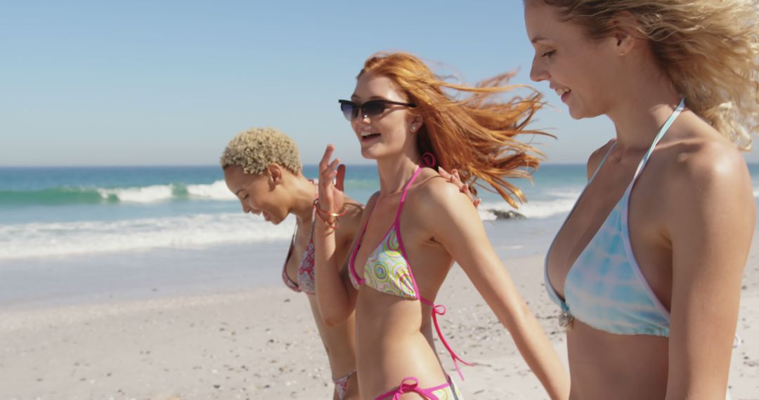 Three Young Women Walking on Sunny Beach in Swimsuits - Free Images, Stock Photos and Pictures on Pikwizard.com