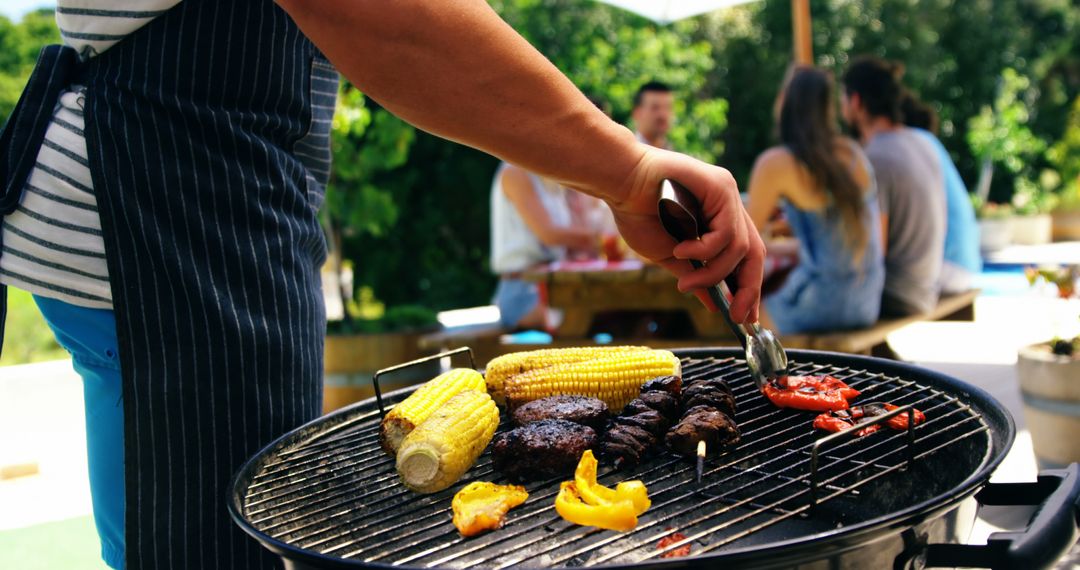 A person enjoys barbecuing a variety of foods at a sunny outdoor social event. - Free Images, Stock Photos and Pictures on Pikwizard.com